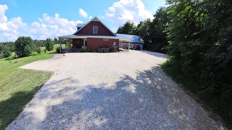 A recovered gravel driveway, smooth and crowned, leading up to a brick home