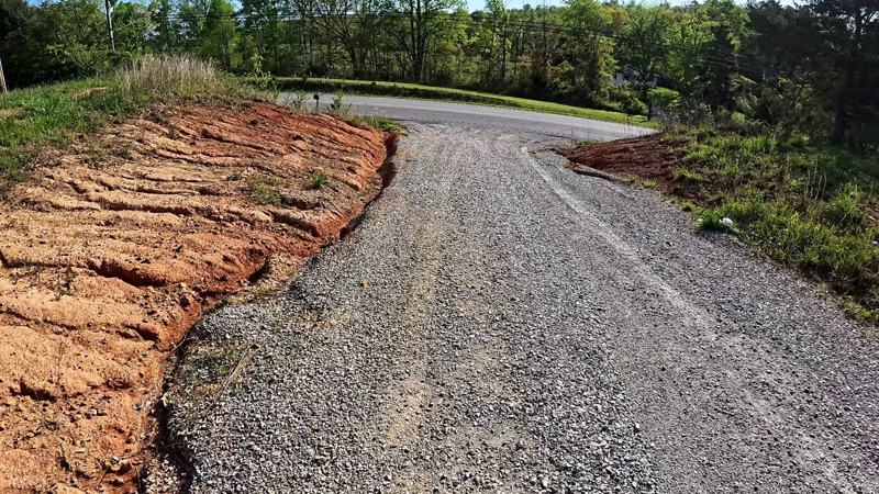A gravel driveway with an eroded red clay bank along one side before the work